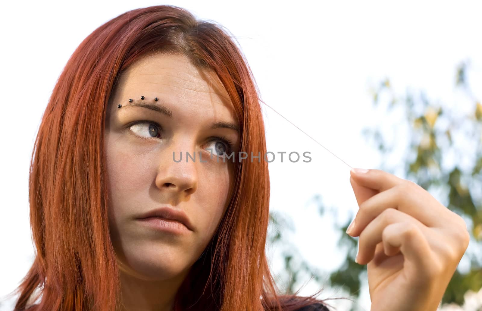 Portrait of a cute redhead looking at one hair with eyes crossed
