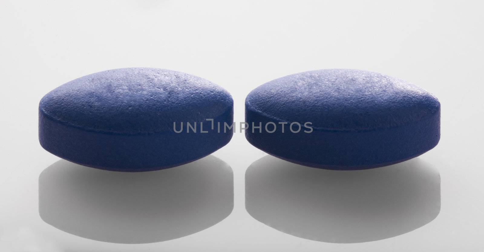 Two blue pills in a close up image.