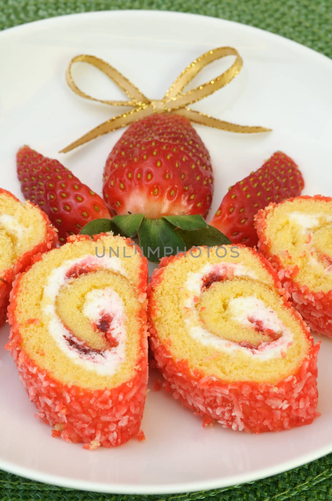 Jam roll cake slices decorated with strawberry and a golden ribbon