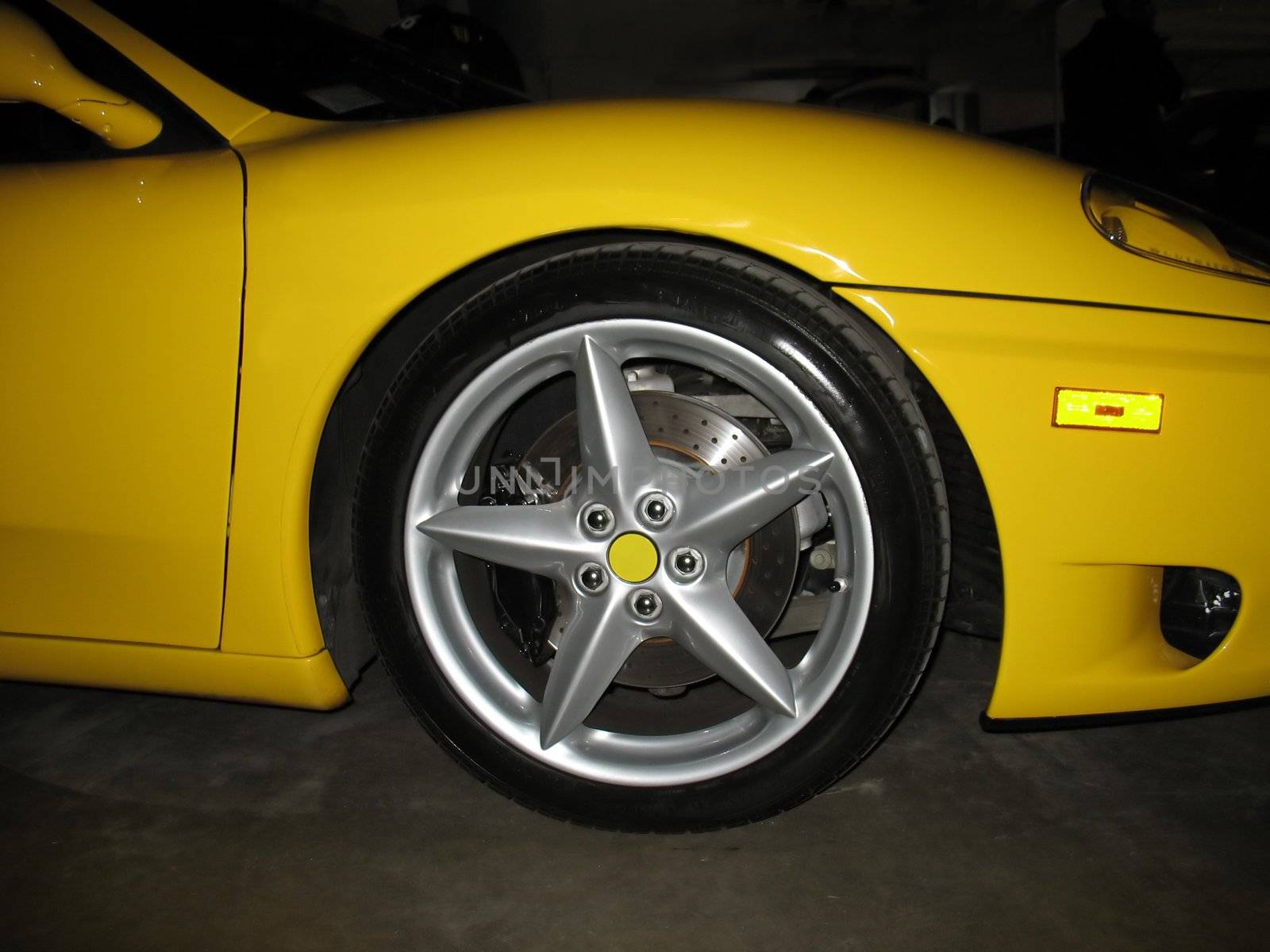 A five star rim on a luxurious, yellow sports coupe.