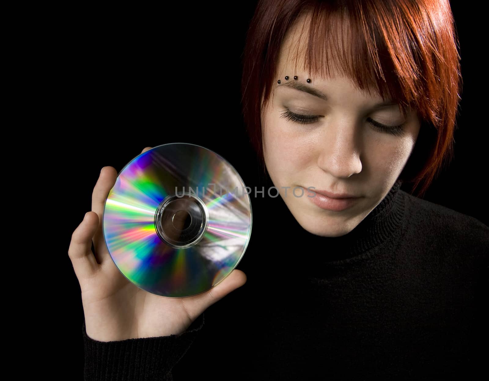 Redhead girl holding a compact disc. Lit with studio lighting, hair light and two umbrelled strobes.