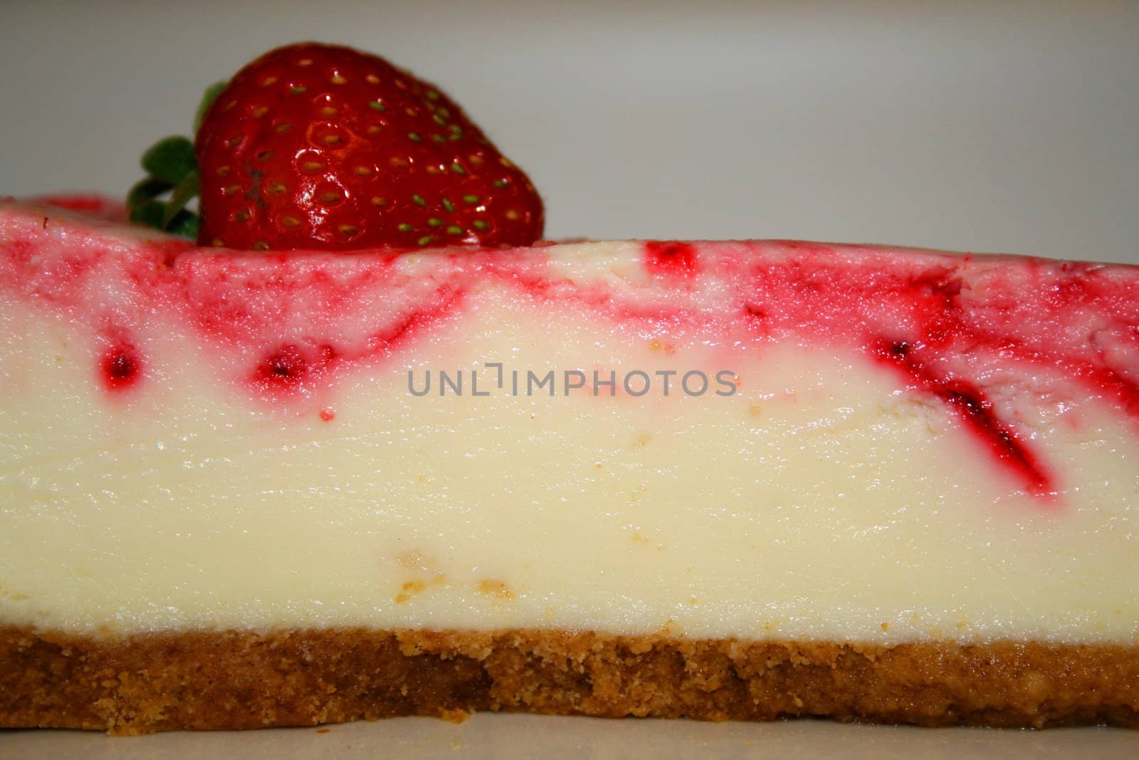 Close up of a strawberry cheesecake on a plate.
