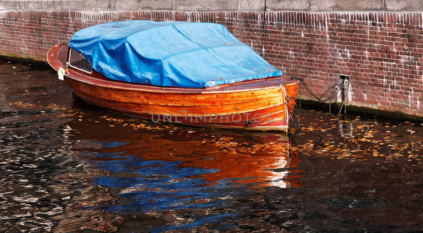 Image of a wooden boat on a canal in Amsterdam during autumn.