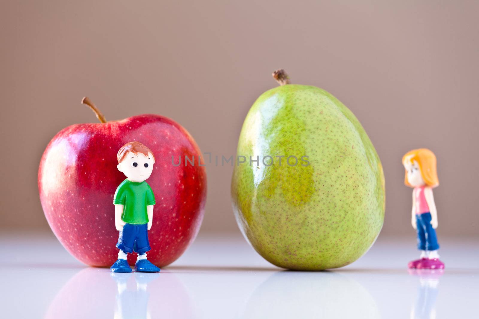 Toy girl and boy disagree over nutrition and healthy choices in front of a green pear and a  red apple. The concepts depicted in this image are nutrition, good food choices, balanced diet and good for you.