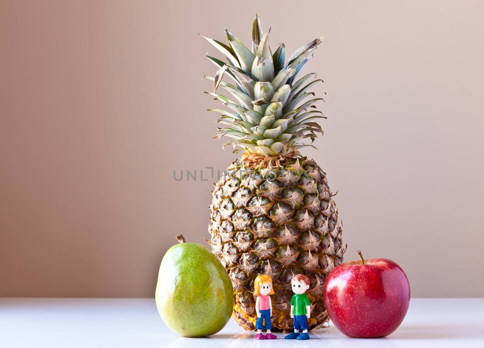 Toy girl and boy overwhelmed by making good food choices. They are standing in front of pineapple and between green pear and red apple. The concepts depicted in this image are nutrition, good food choices, balanced diet and good for you.