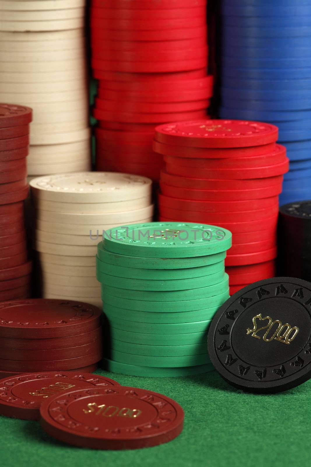 Photo of stacks of generic antique poker chips. Focus on green chips and twenty dollar chip.