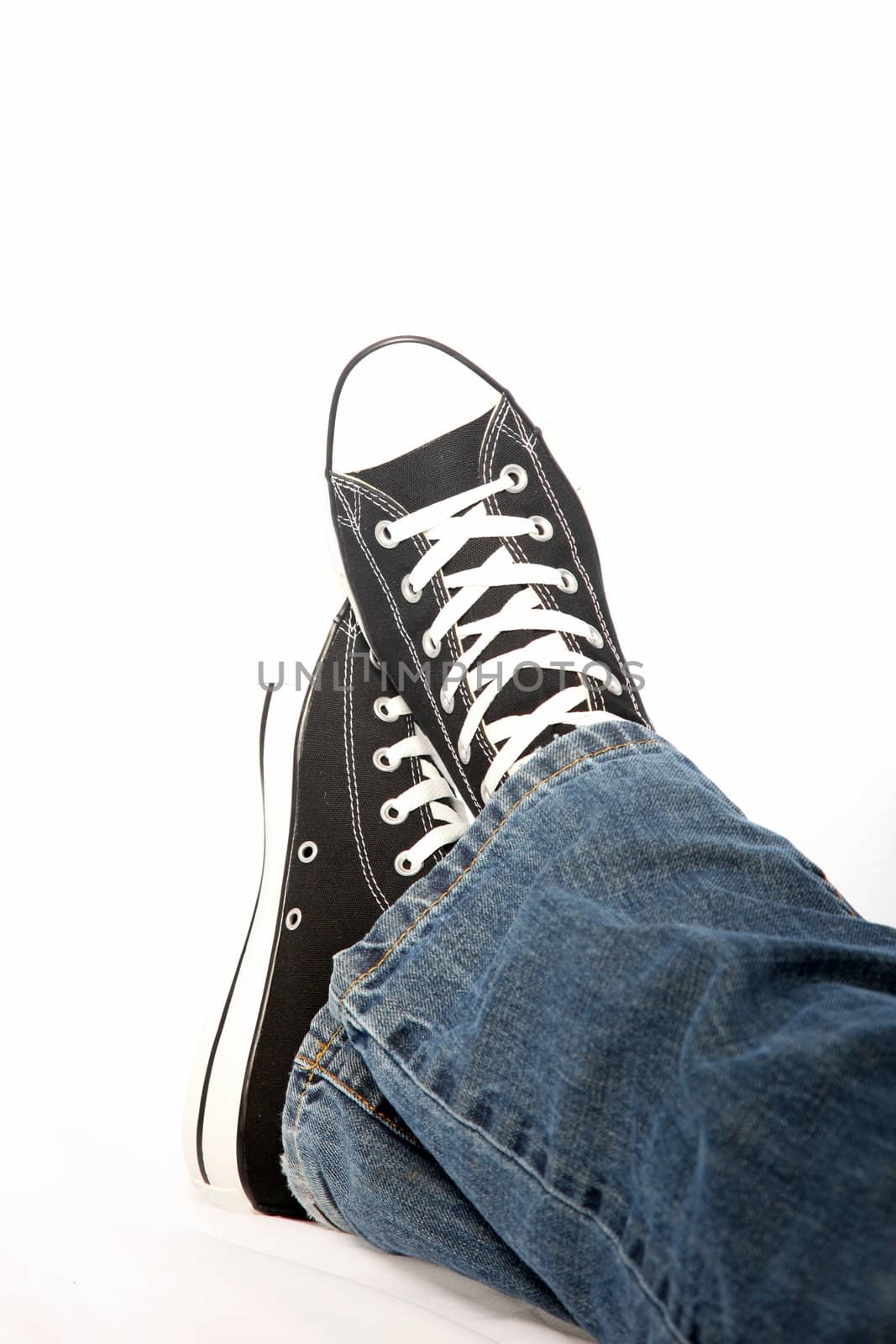 Cropped view of the feet of a person wearing jeans and sneakers isolated on white
