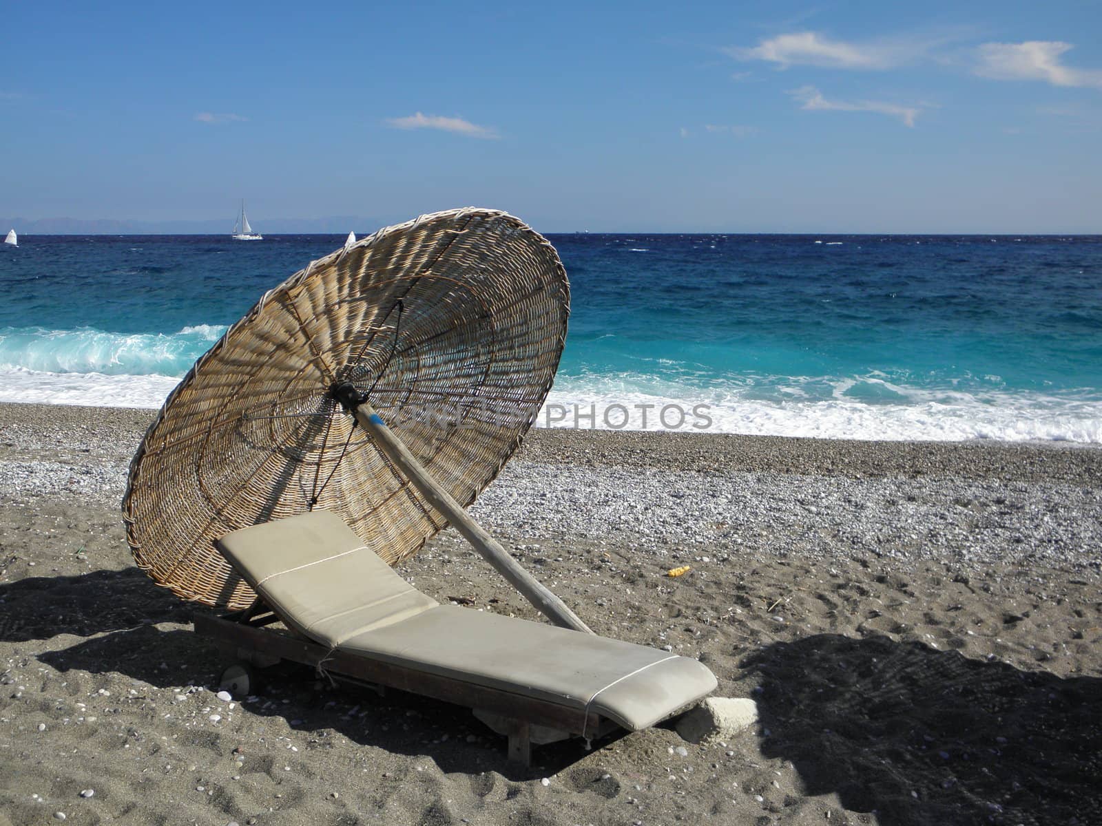 Sun-bed with parasol on a beautiful beach in Greece