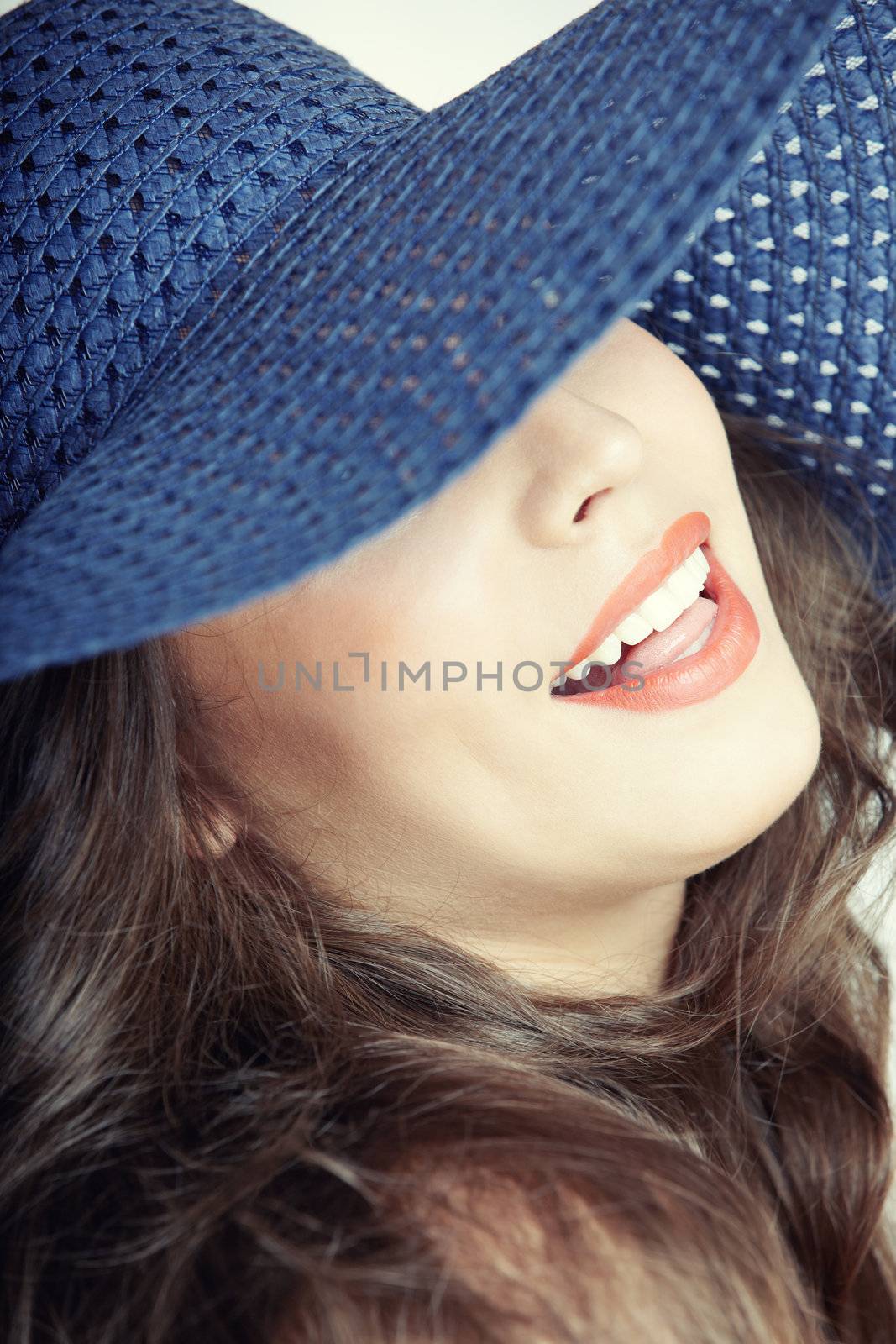 Laughing lady with blue hat on a studio background