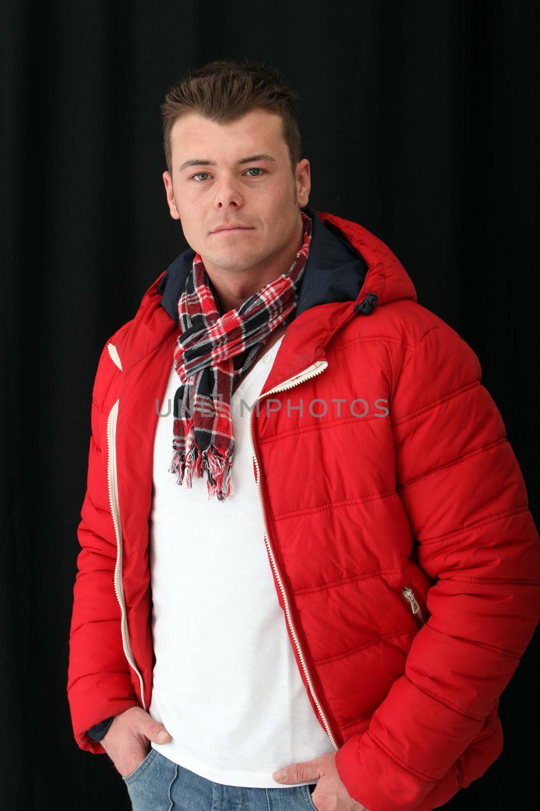 Muscular man wearing red jacket posing against the black background