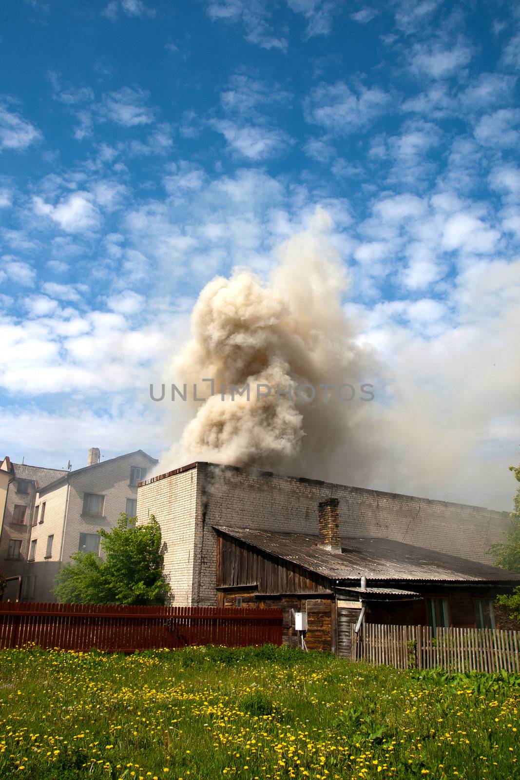 fire in city building, with white smoke to the blue sky