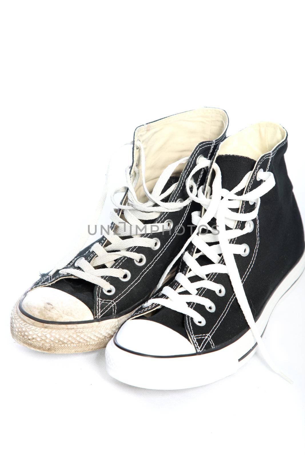 Pair of lace up sneakers or trainers in black canvas with white laces on a white background