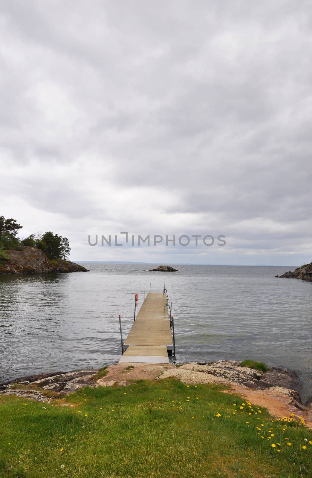 Wooden pier in calm lake with small island.