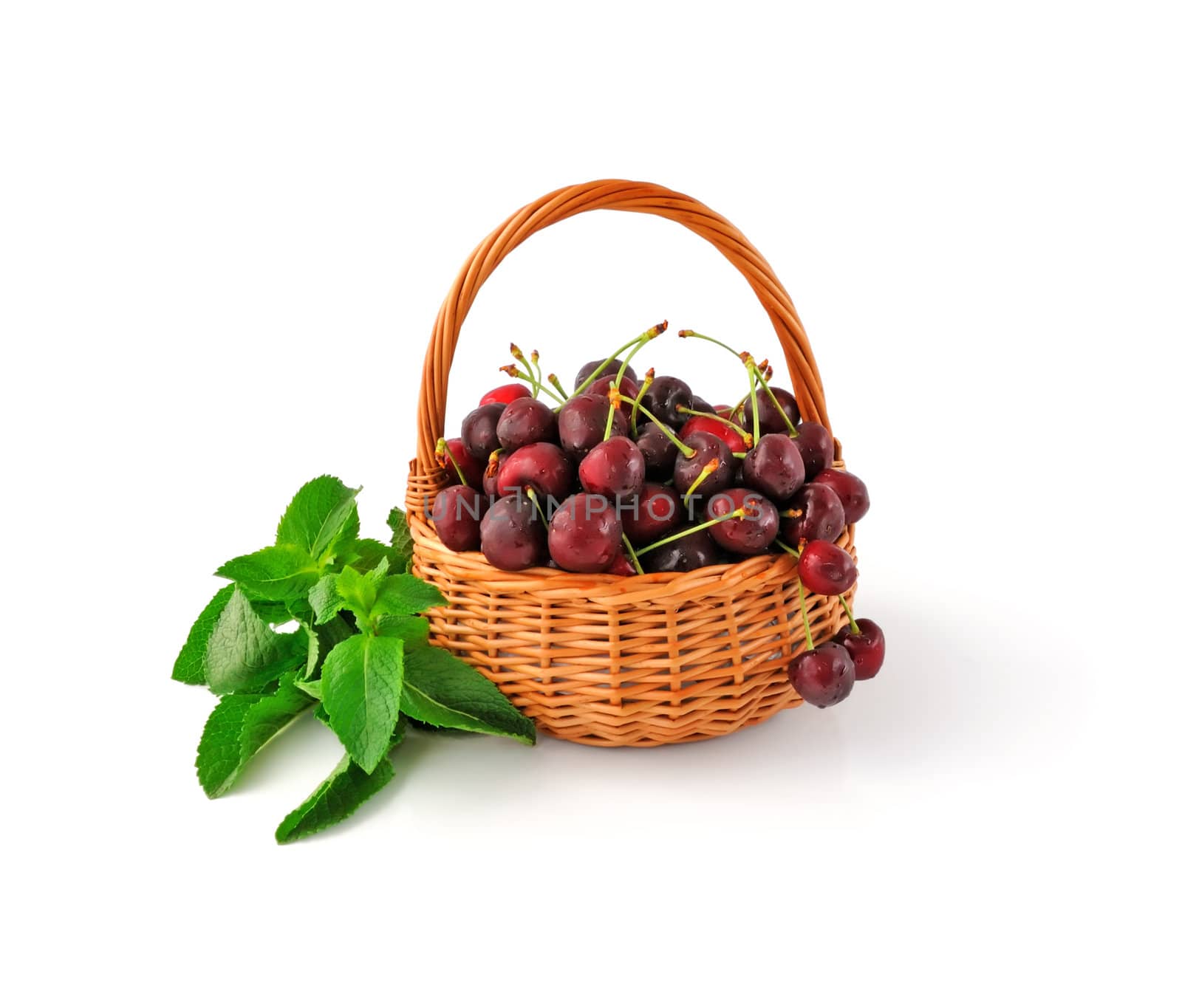 Basket with fresh cherries and mint on a white background