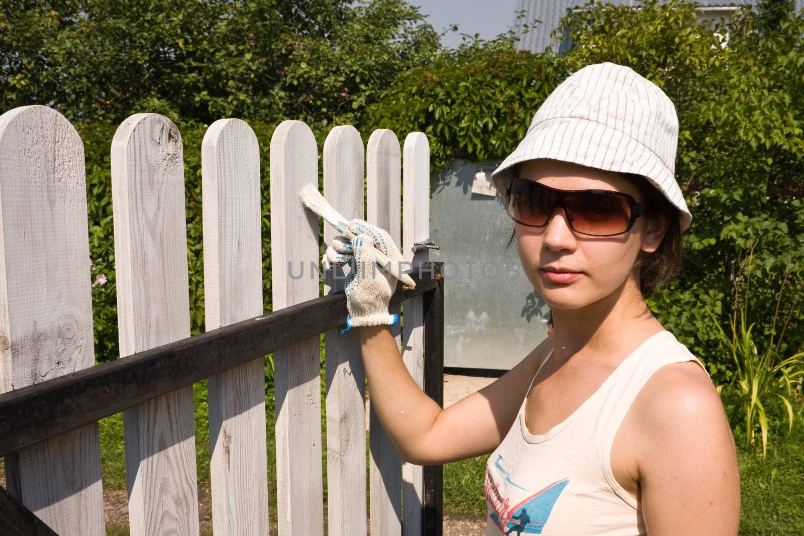 Beautiful girl colours the wooden fence by nikolpetr