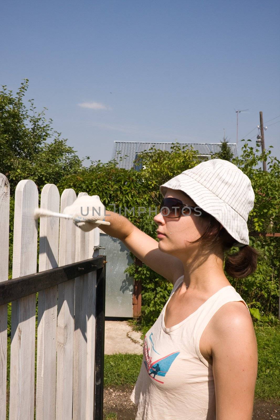 Beautiful girl colours the wooden fence