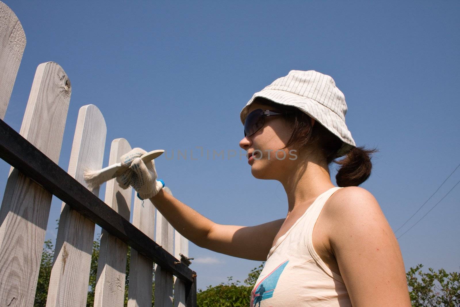 Beautiful girl colours the wooden fence