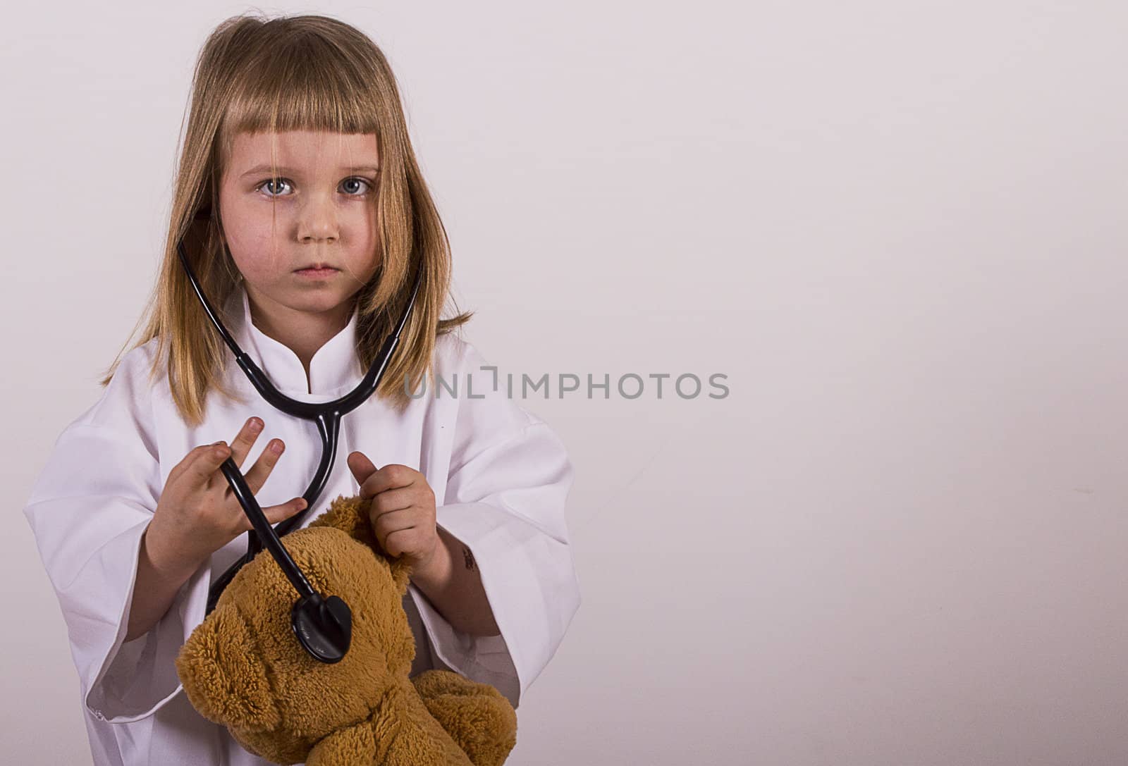 little girl is examinating her bear, little doctor with stethoscope