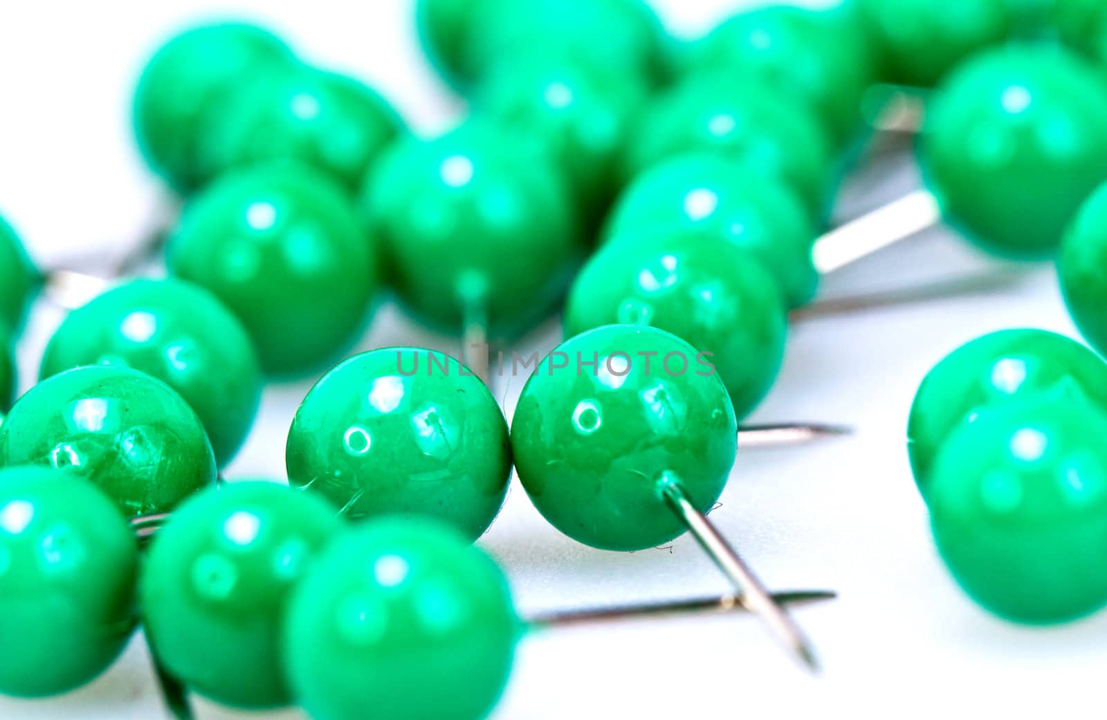 Green color plastic pushpin on white background