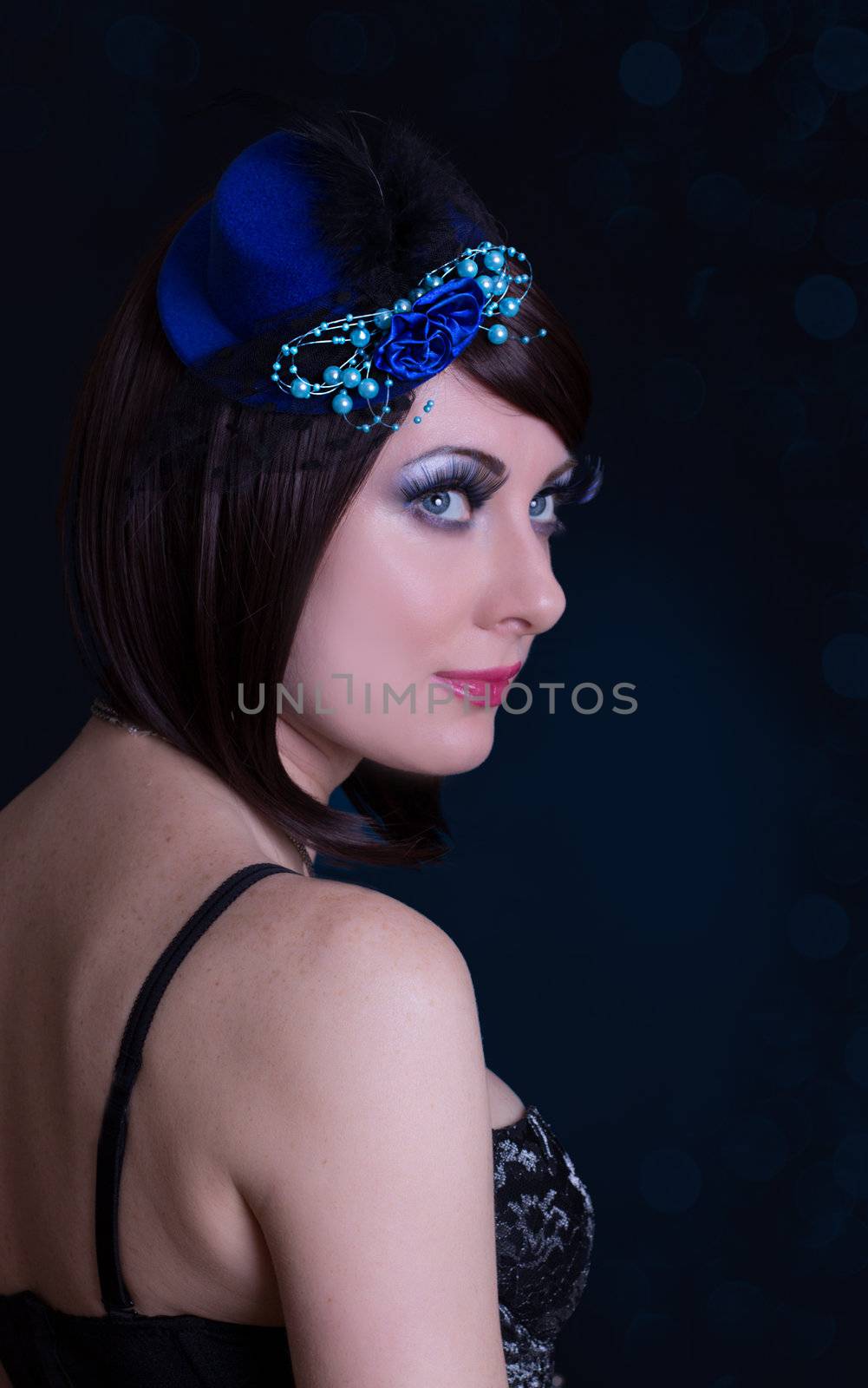 Retro styled beauty woman portrait with hat and long lashes on black