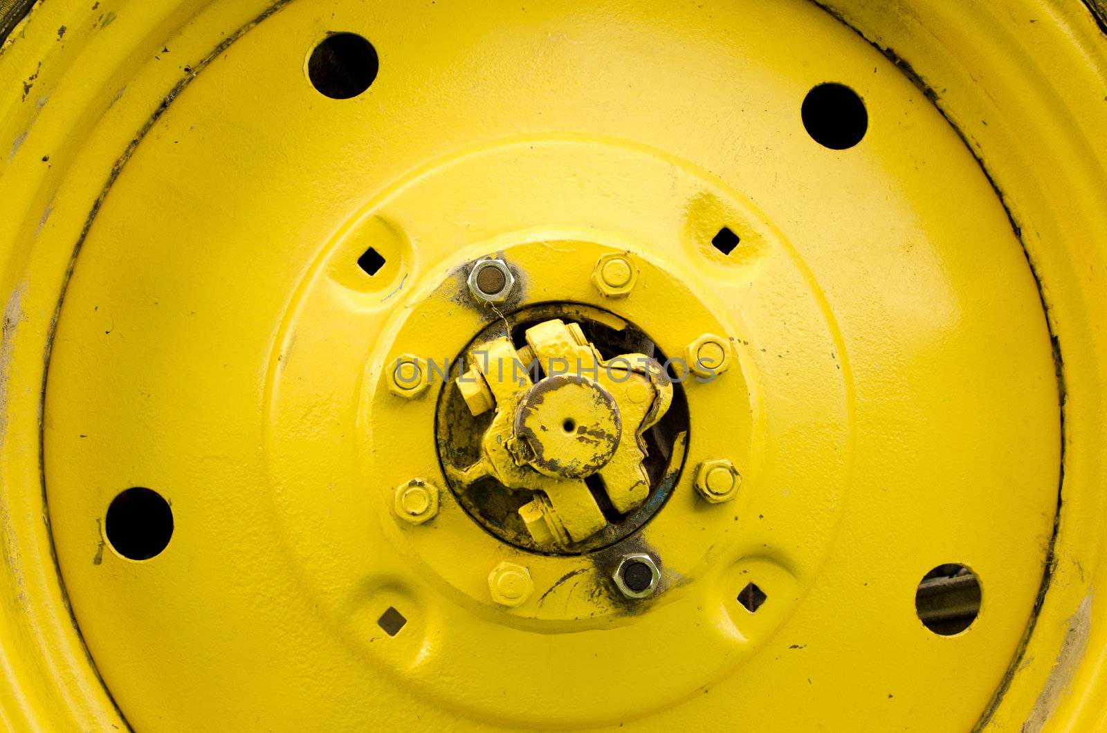 Yellow tractor wheel closeup details bolts nuts holes