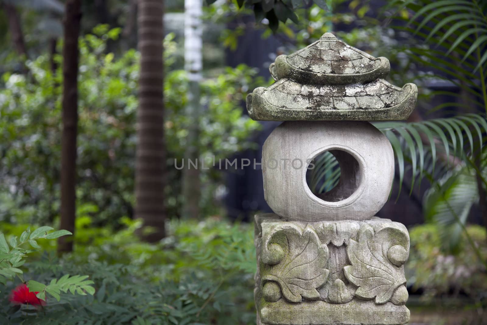 Stone asian statue outdoors in green park.