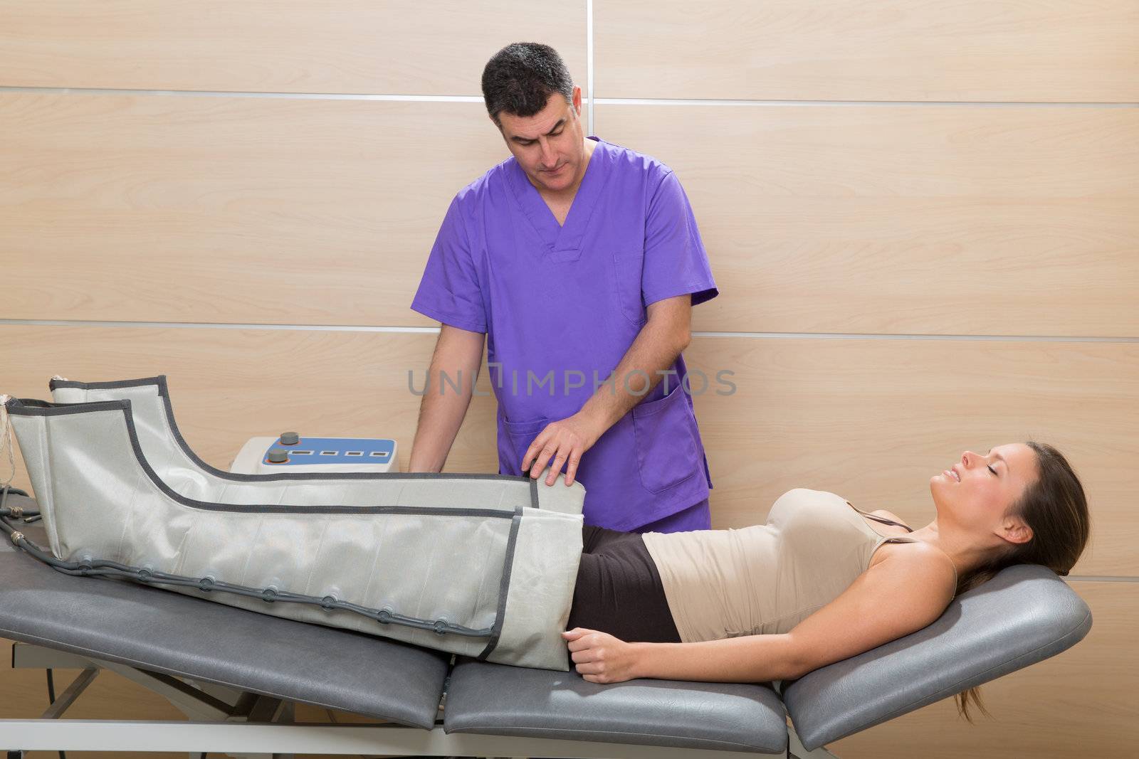 Doctor checking legs pressotherapy machine on woman by lunamarina