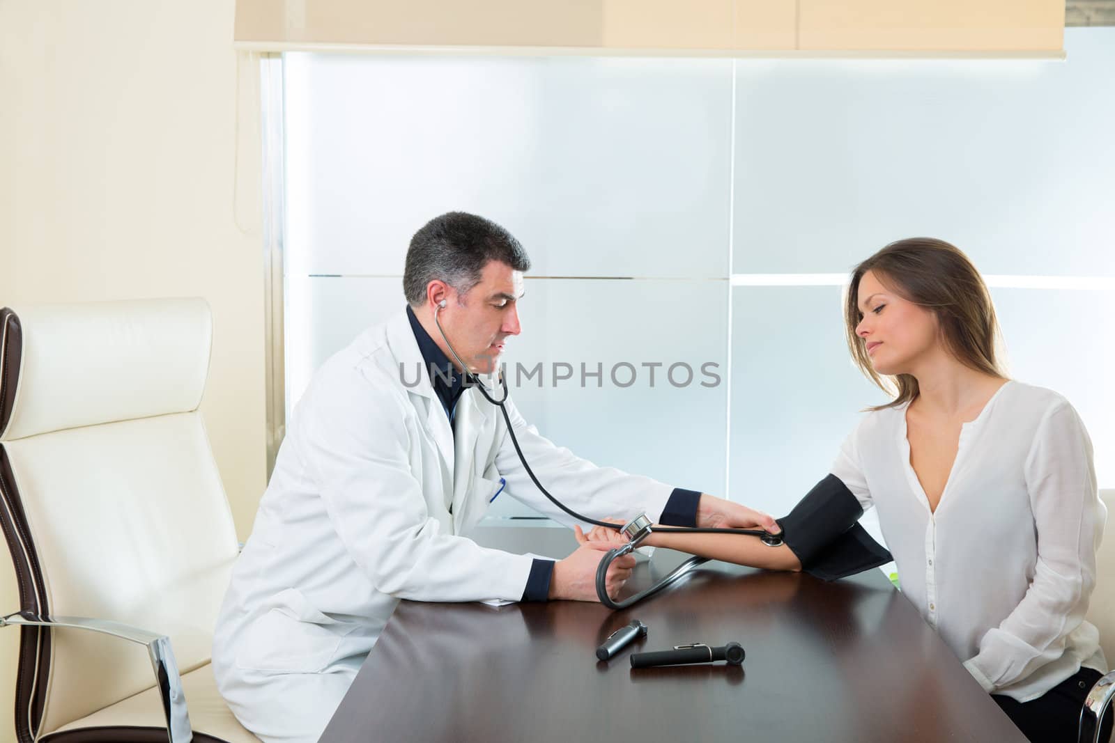 Doctor man checking blood pressure cuff on woman patient arm on hospital office