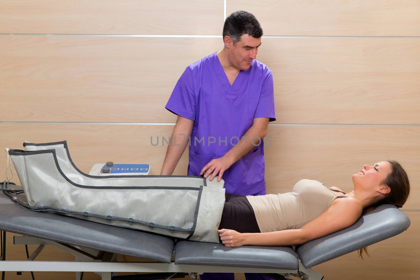 Doctor checking legs pressotherapy machine on woman patient in hospital bed