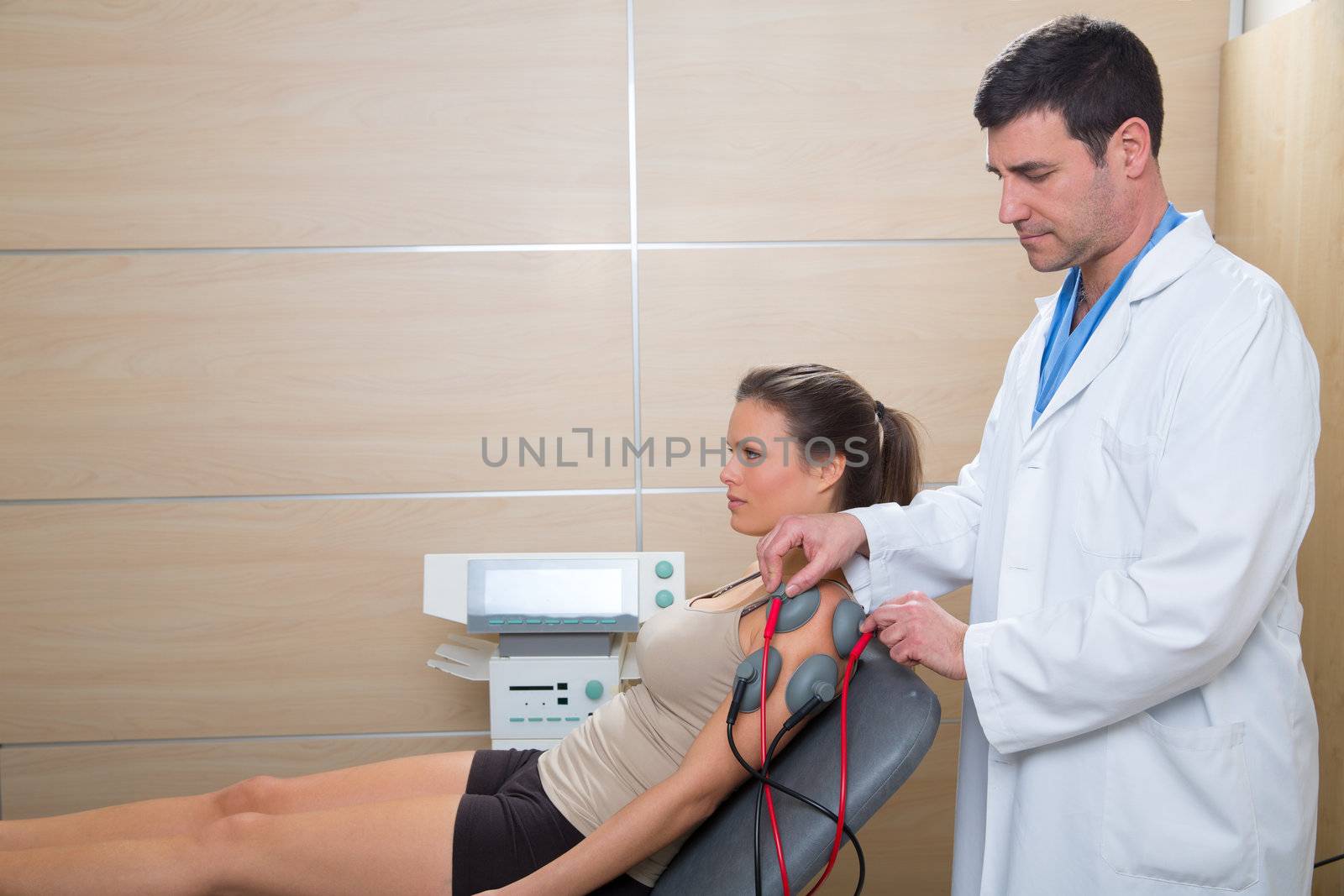 Doctor therapist checking arm shoulder muscle electrostimulation to woman in hospital