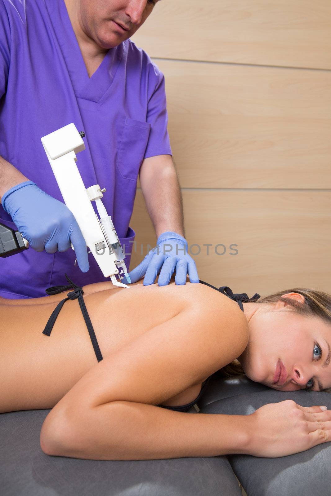 Back lumbar mesotherapy gun doctor therapy with woman patient on bed