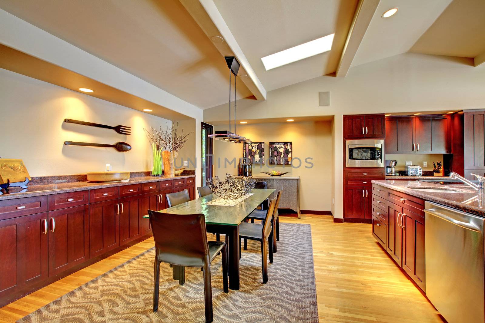 Luxury modern dining room with mahogany kitchen and glass table.