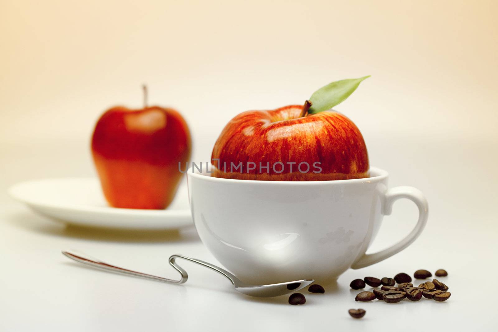 apple in a cup, saucer, spoon and coffee beans