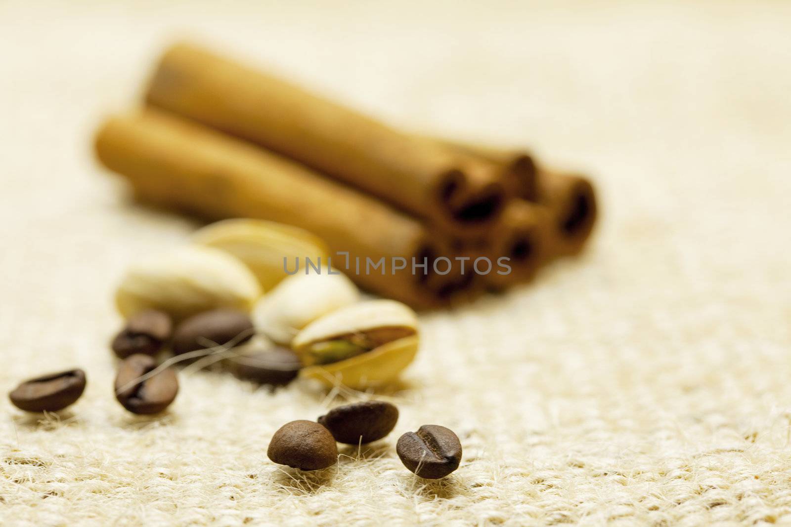 cinnamon , coffee beans and pistachios on linen fabric by jannyjus