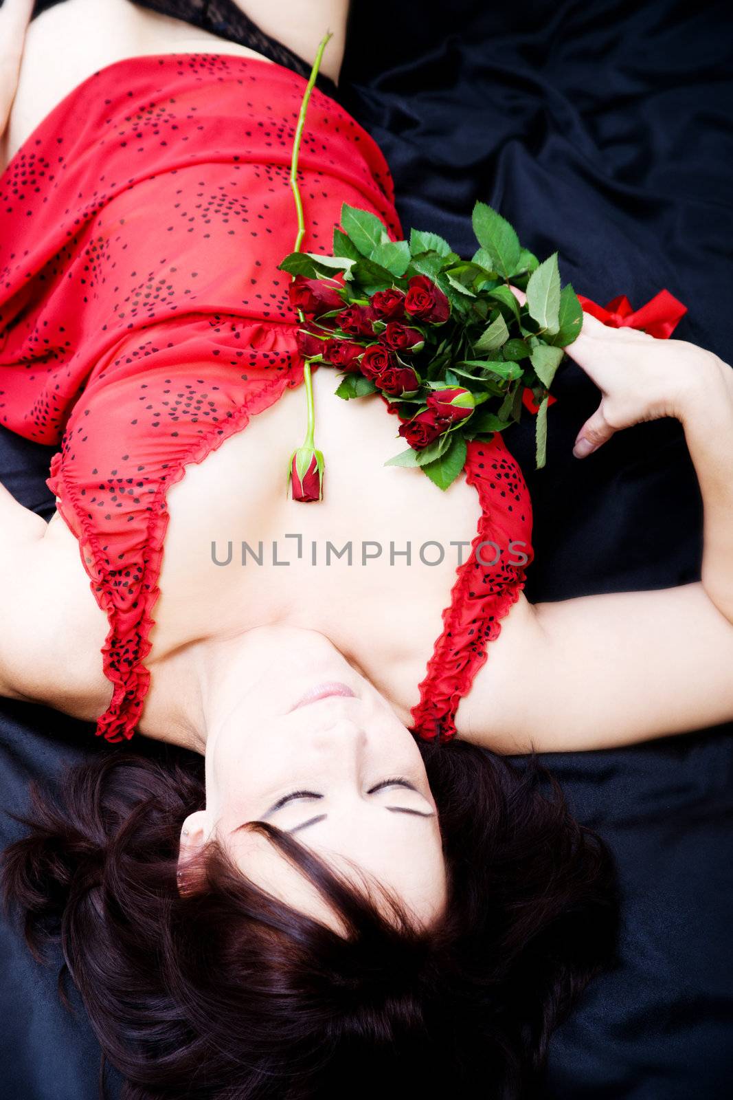 woman lying on black sheet with red roses