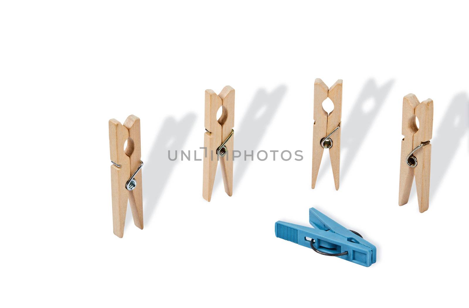 Abstract act of violence. Closeup of four white wooden pegs are vertical position, horizontally near them is a plastic clothespin blue. Long shadows emphasize the situation. File includes a clipping path.