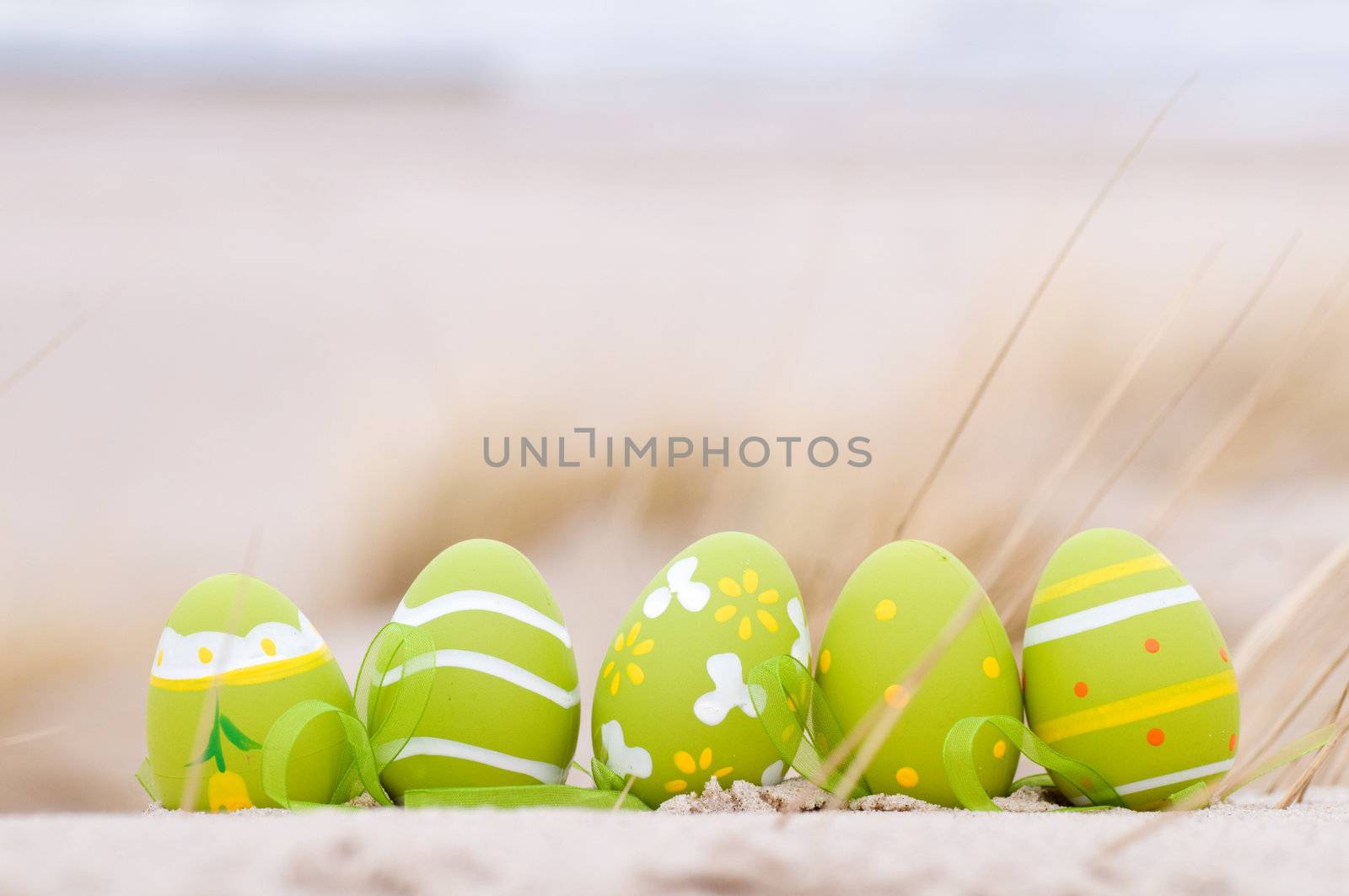 Easter decorated eggs on sand. Beach and ocean in the background