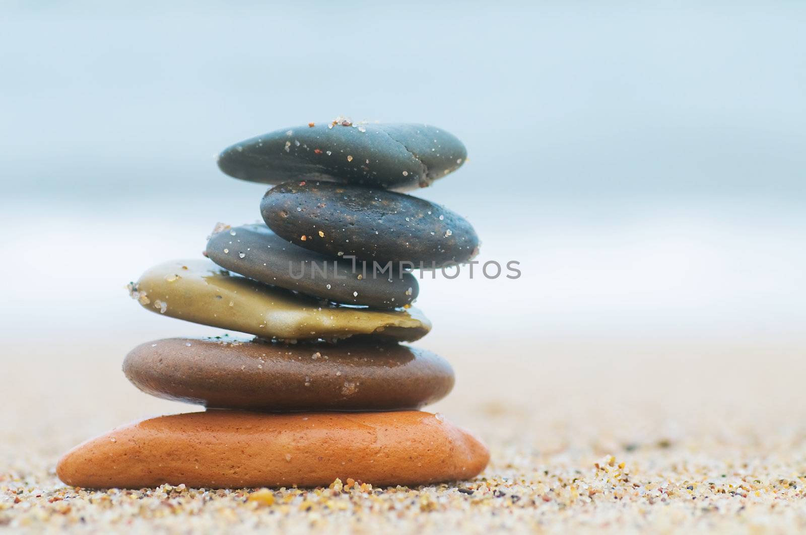 Stack of beach stones on sand. Ocean in the background