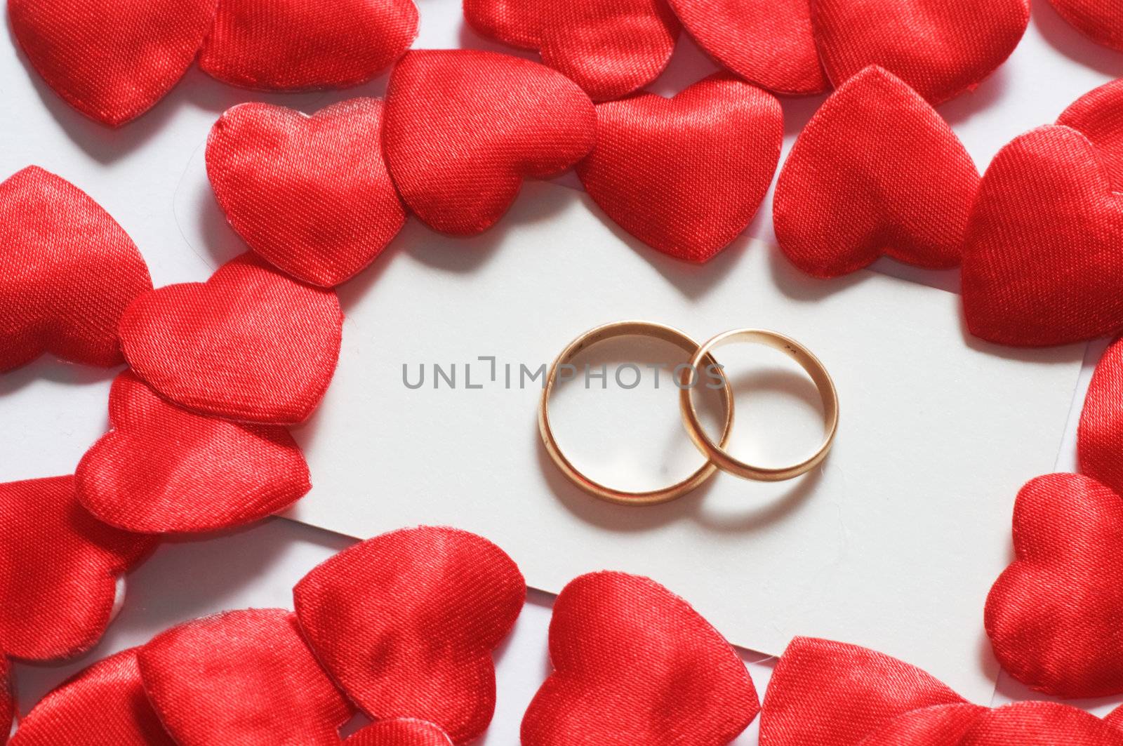 Two wedding rings surrounded by little hearts