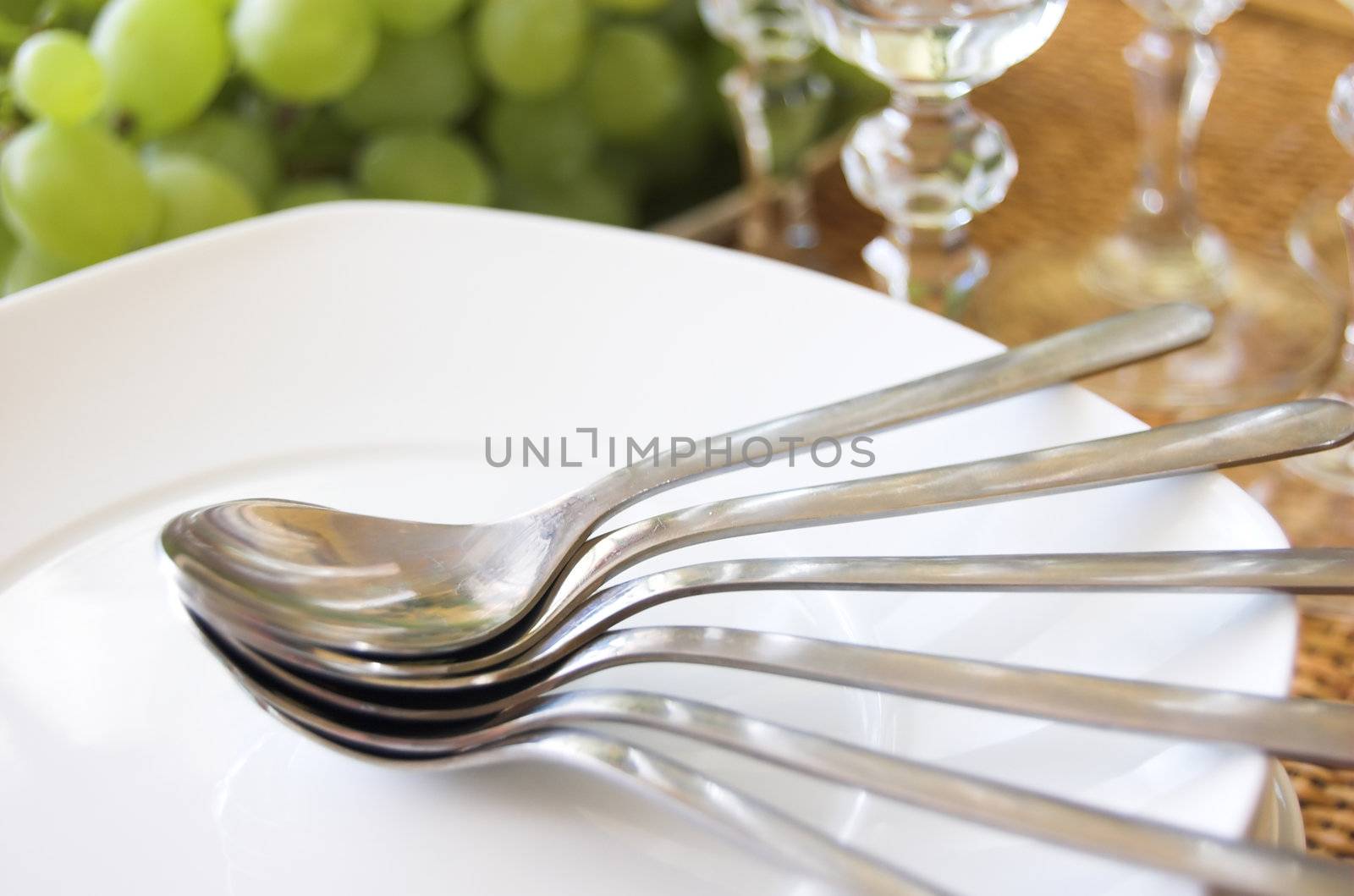 Luxury table setting with bunch of grapes, plate, spoon and wine glasses