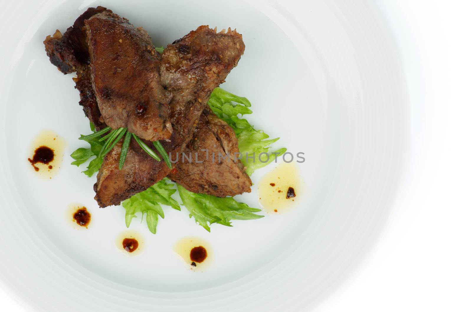 Slices of Delicious Roasted Beef with Spices and  Rosemary closeup on White Plate with Lettuce. Top View