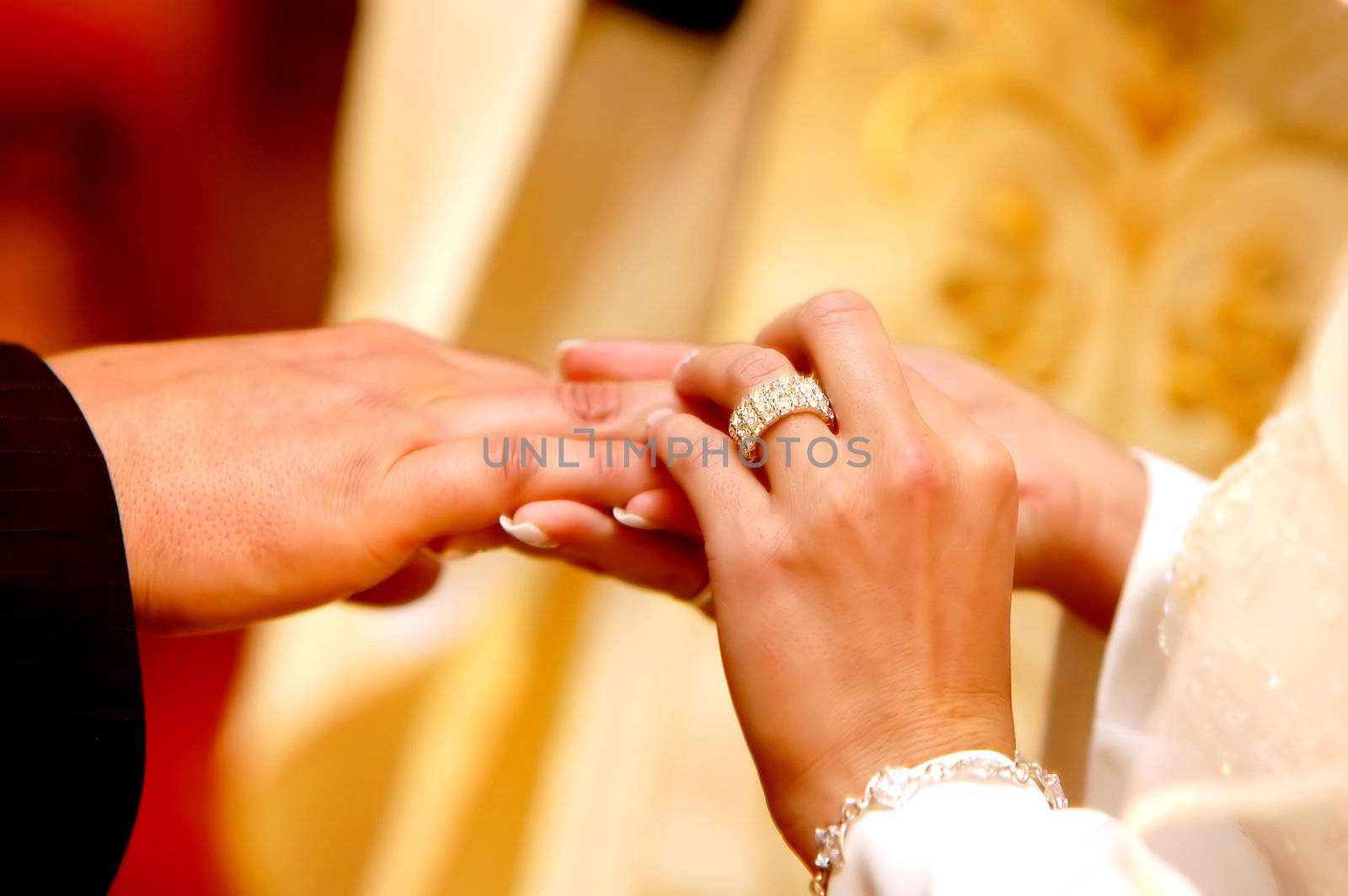 Wedding ceremony, Groom put a ring on bride hand.