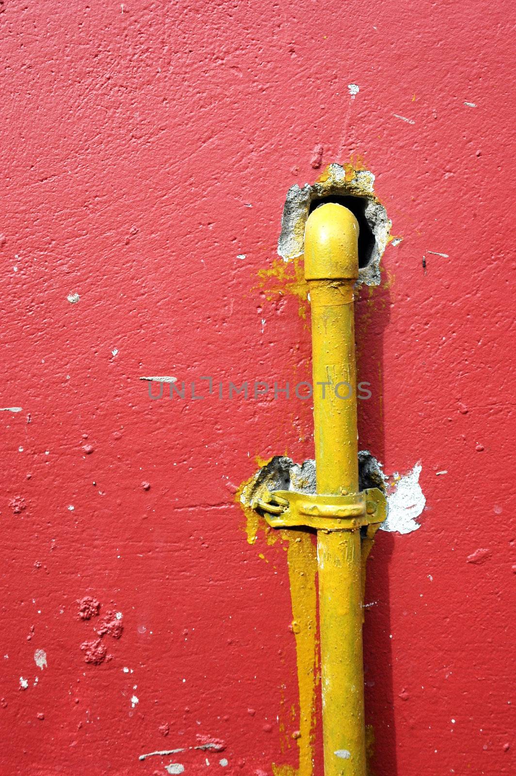yellow iron pipe on the red wall