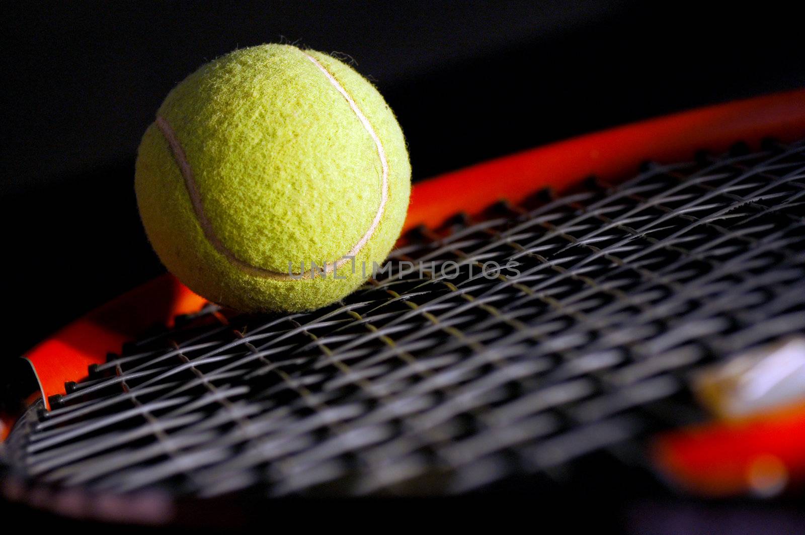 Tennis equipment - ball and racket on black. Soft light, shallow depth of field.
