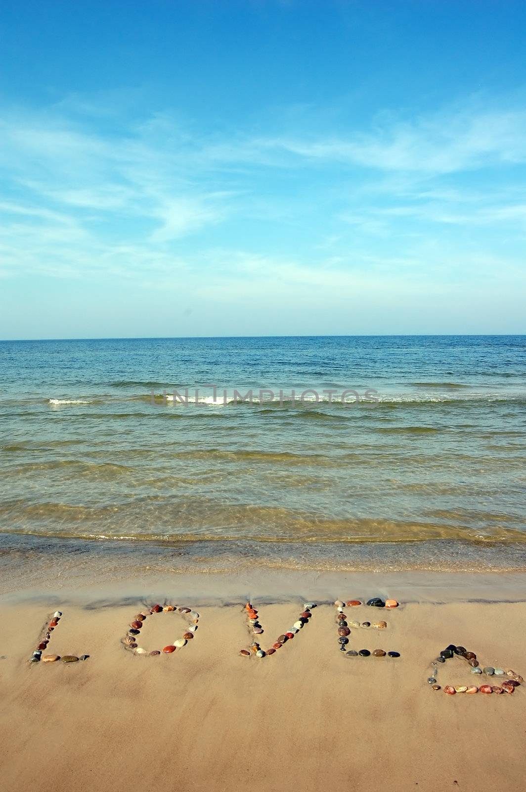 Word LOVE on beach sand, made from rocks