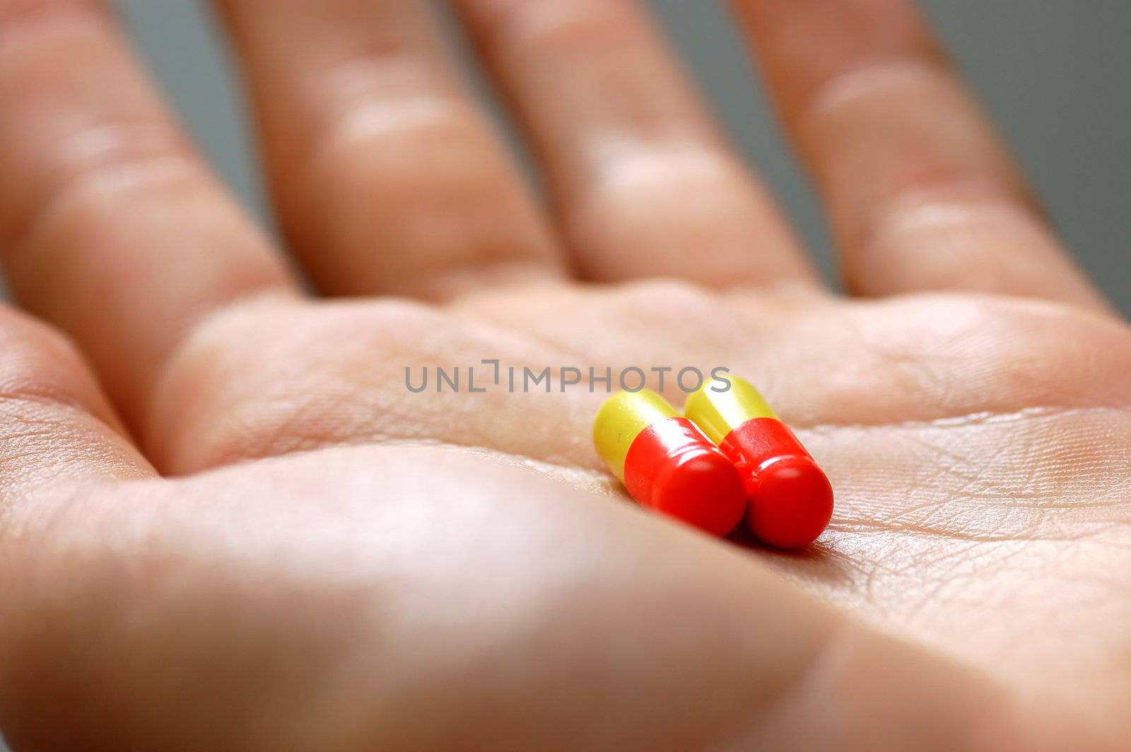 Taking pills. Hand with two capsules