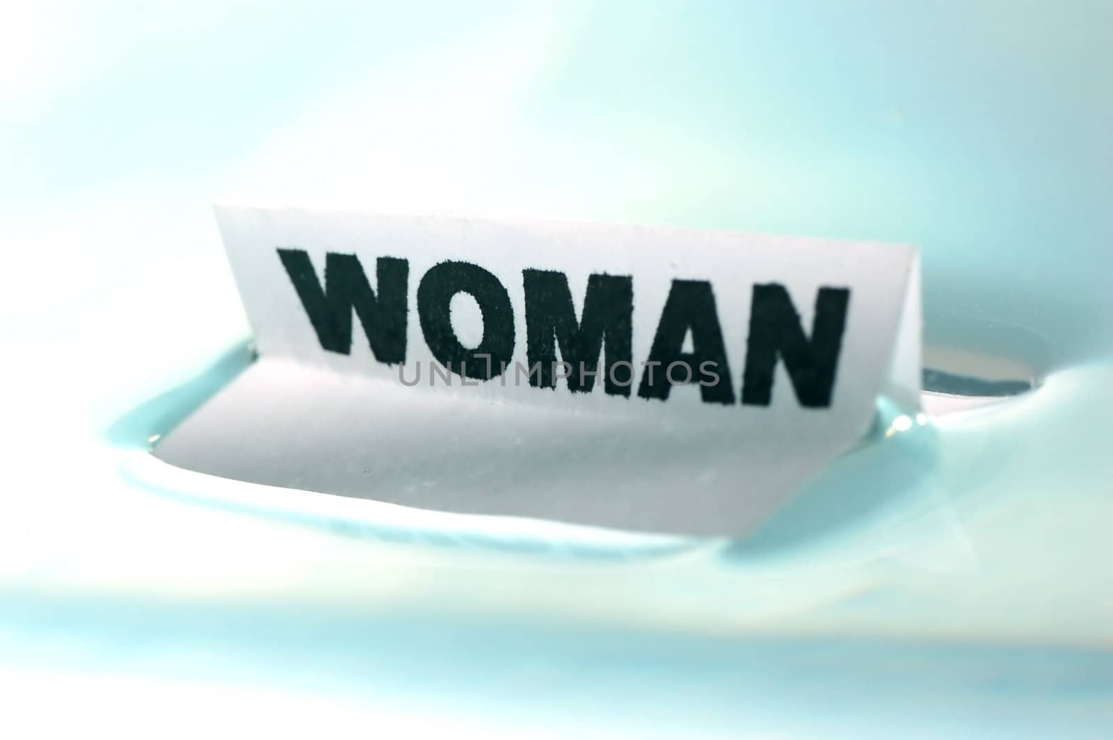Card floating on water surface with printed word: WOMAN