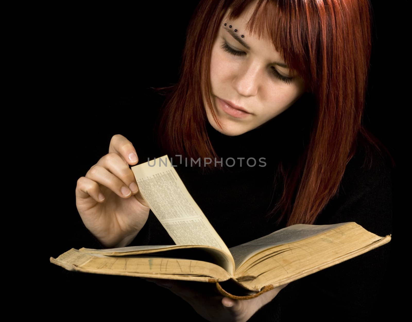 A beautiful redhead girl studying from a book.

Studio shot.