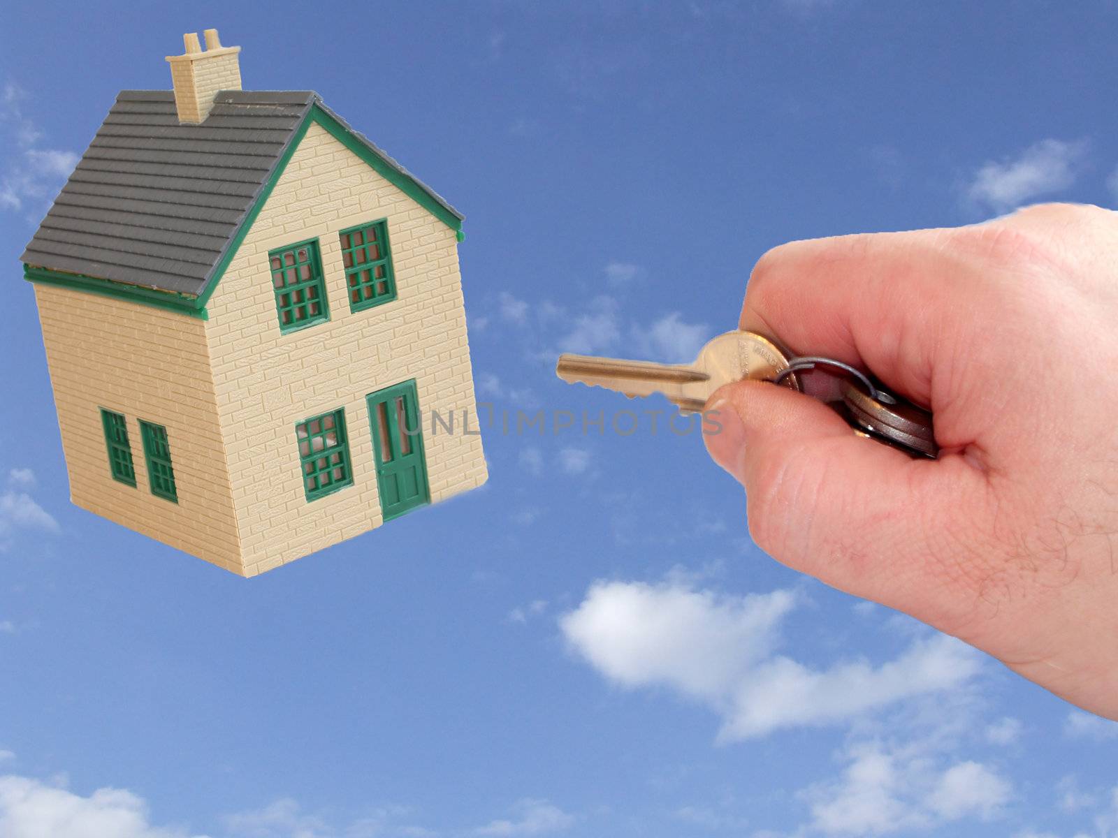 house and key in hand to open door on a sky back ground giving image of dreaming of a new house