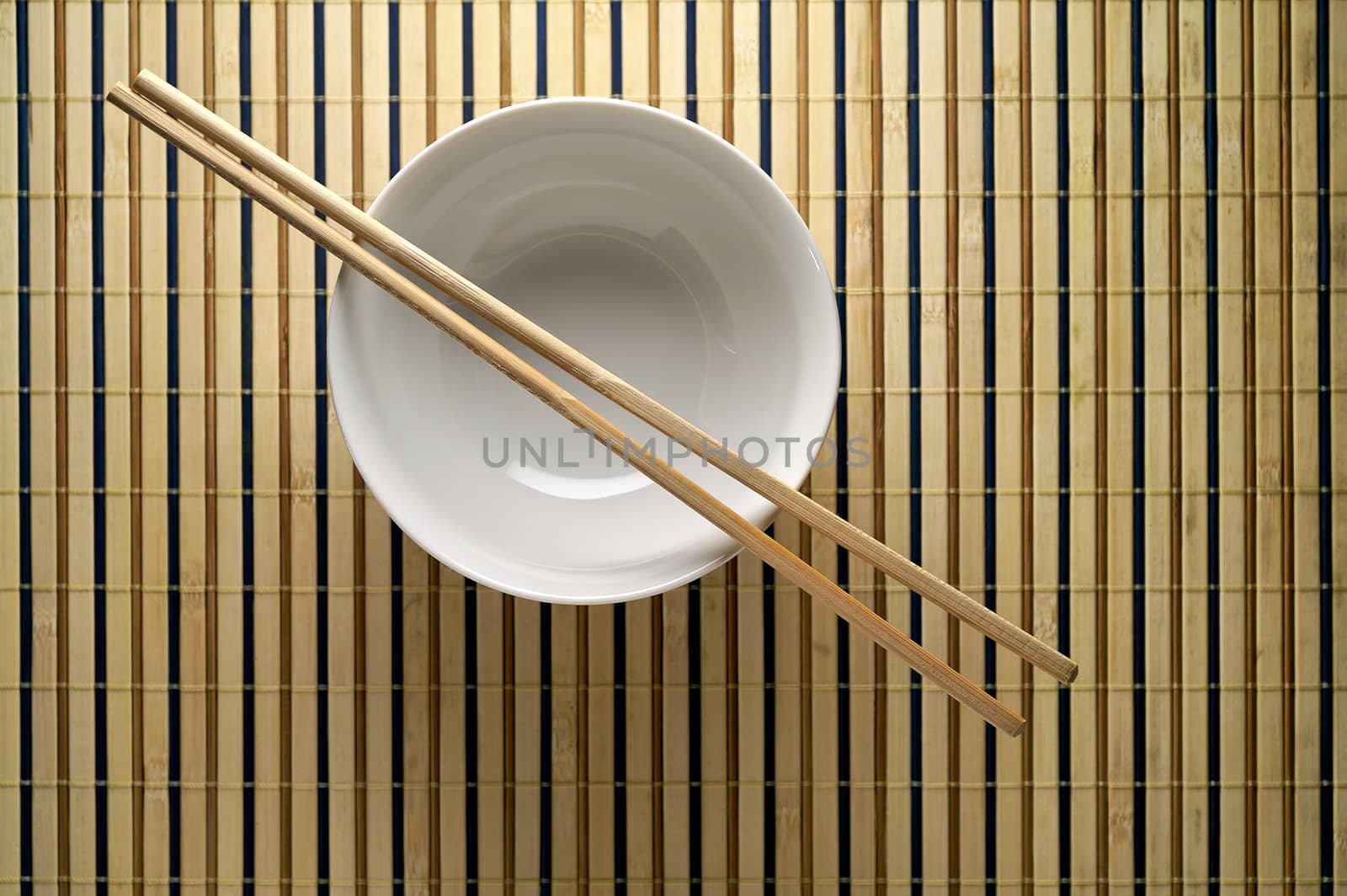 Bowl and chopsticks on bamboo mat